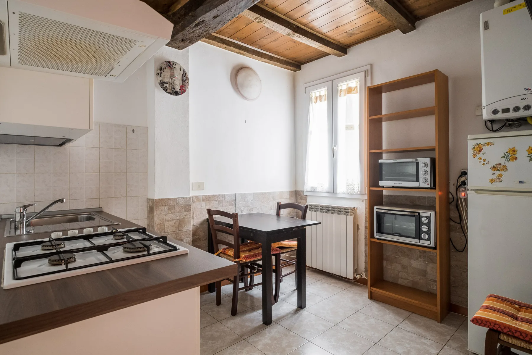 A compact kitchen and dining area with a table beside a bright window.