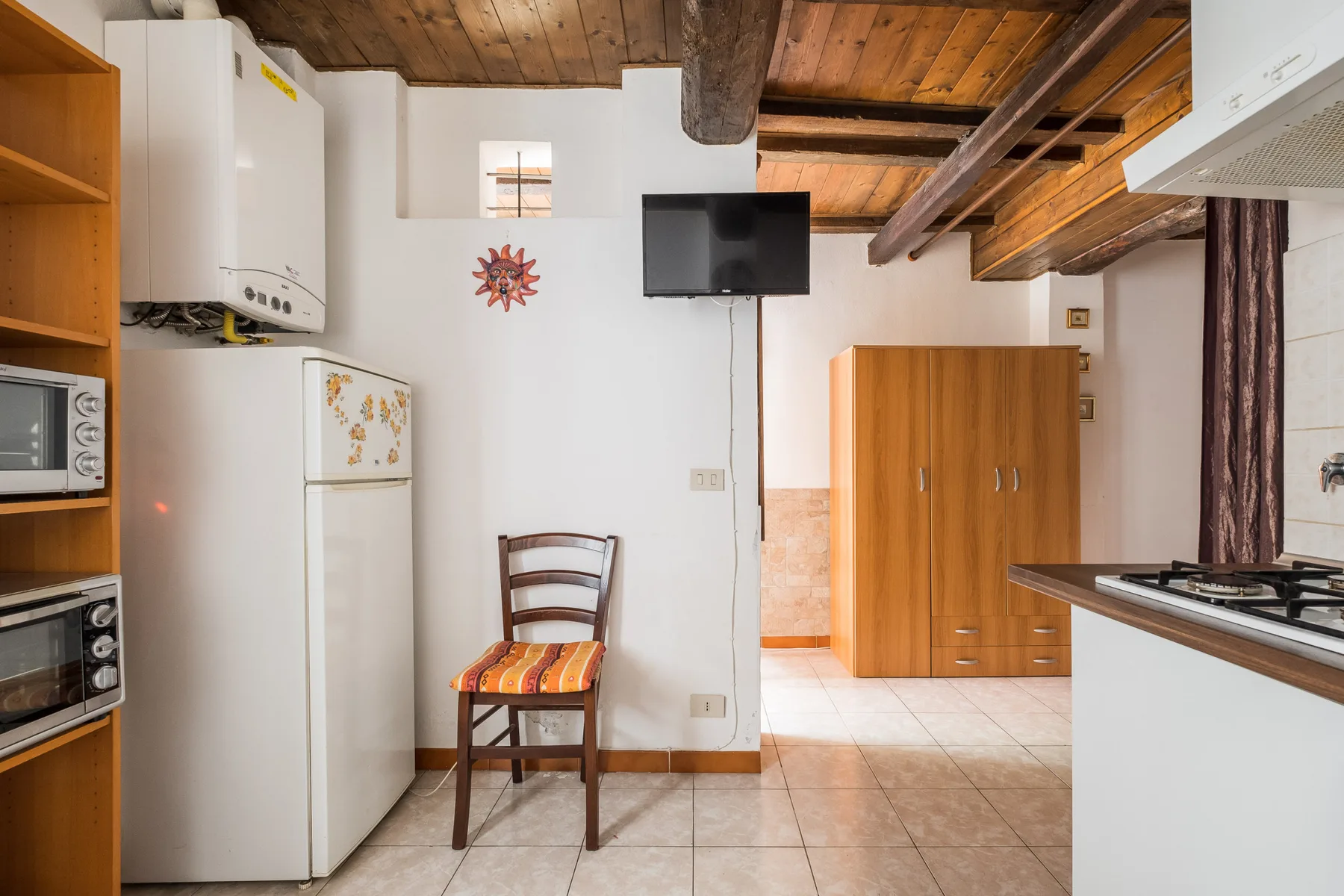 A compact kitchen and dining area with wood ceiling beams and a small table.