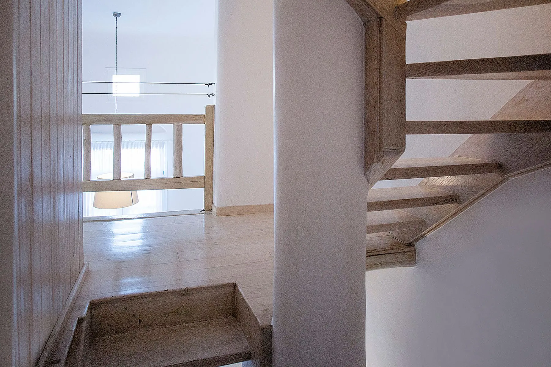 An interior staircase with wooden steps and a bright landing.