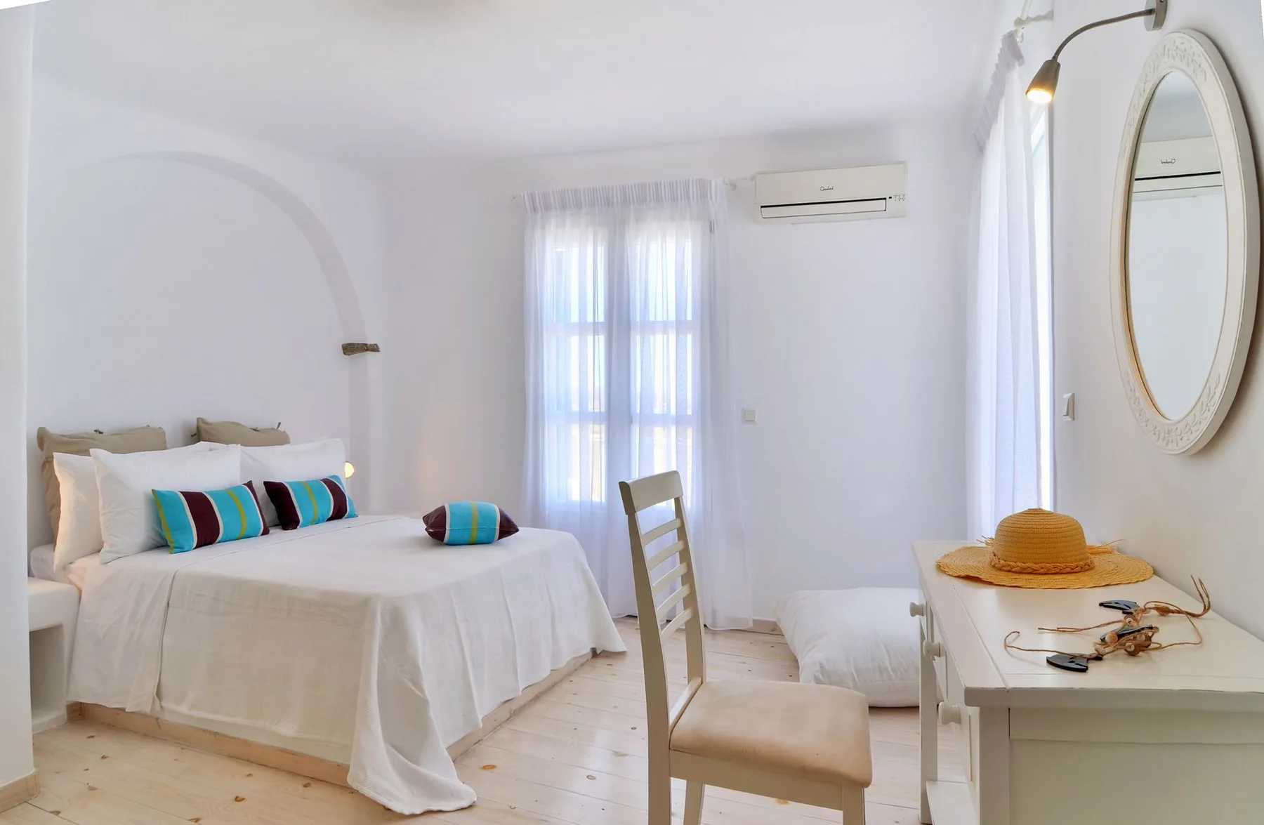 A bright bedroom with a neatly made bed and a desk by the window.