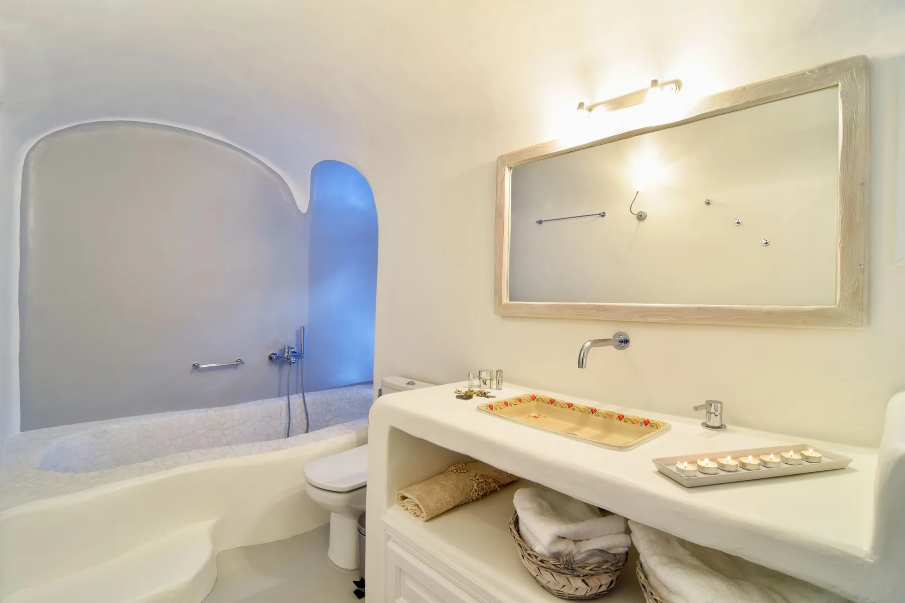 A bathroom with a bathtub, toilet, and wide sink counter.