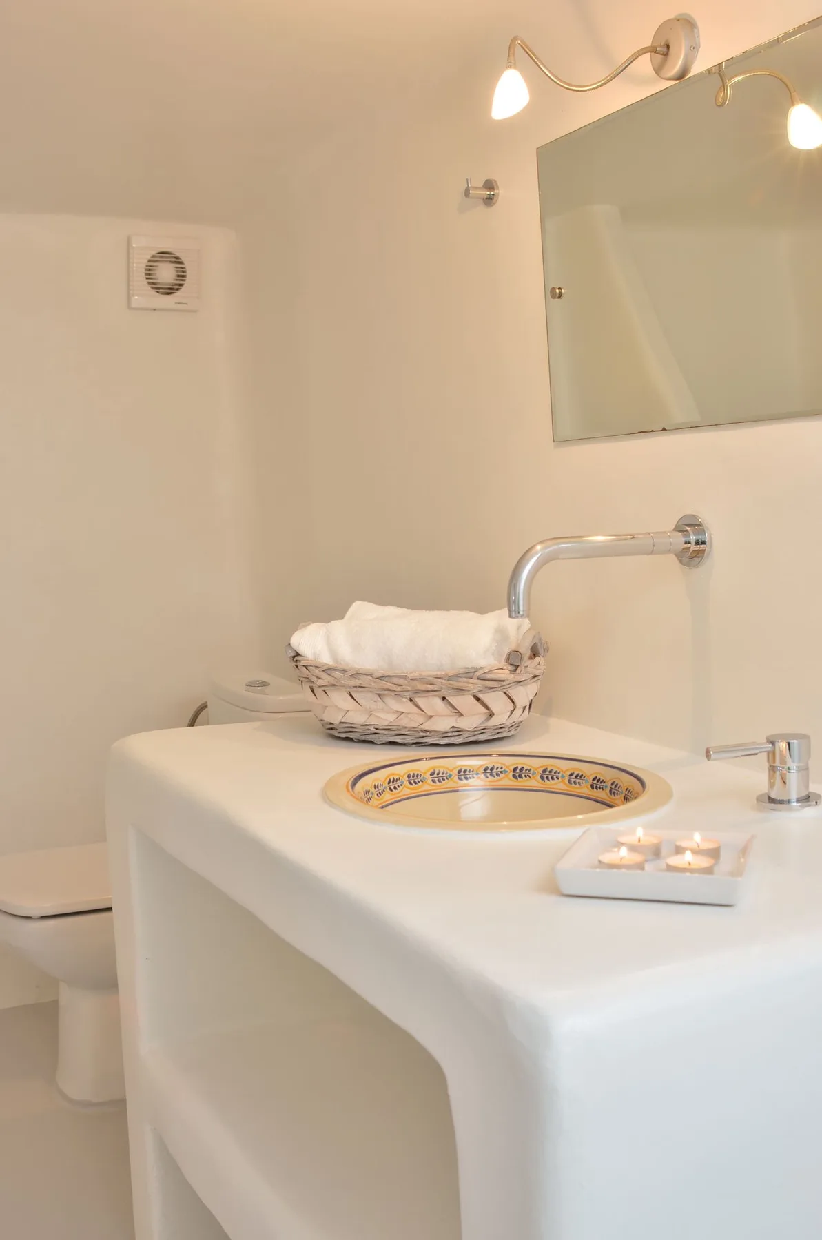 A bright bathroom with a white vanity, basin, and wall mirror.