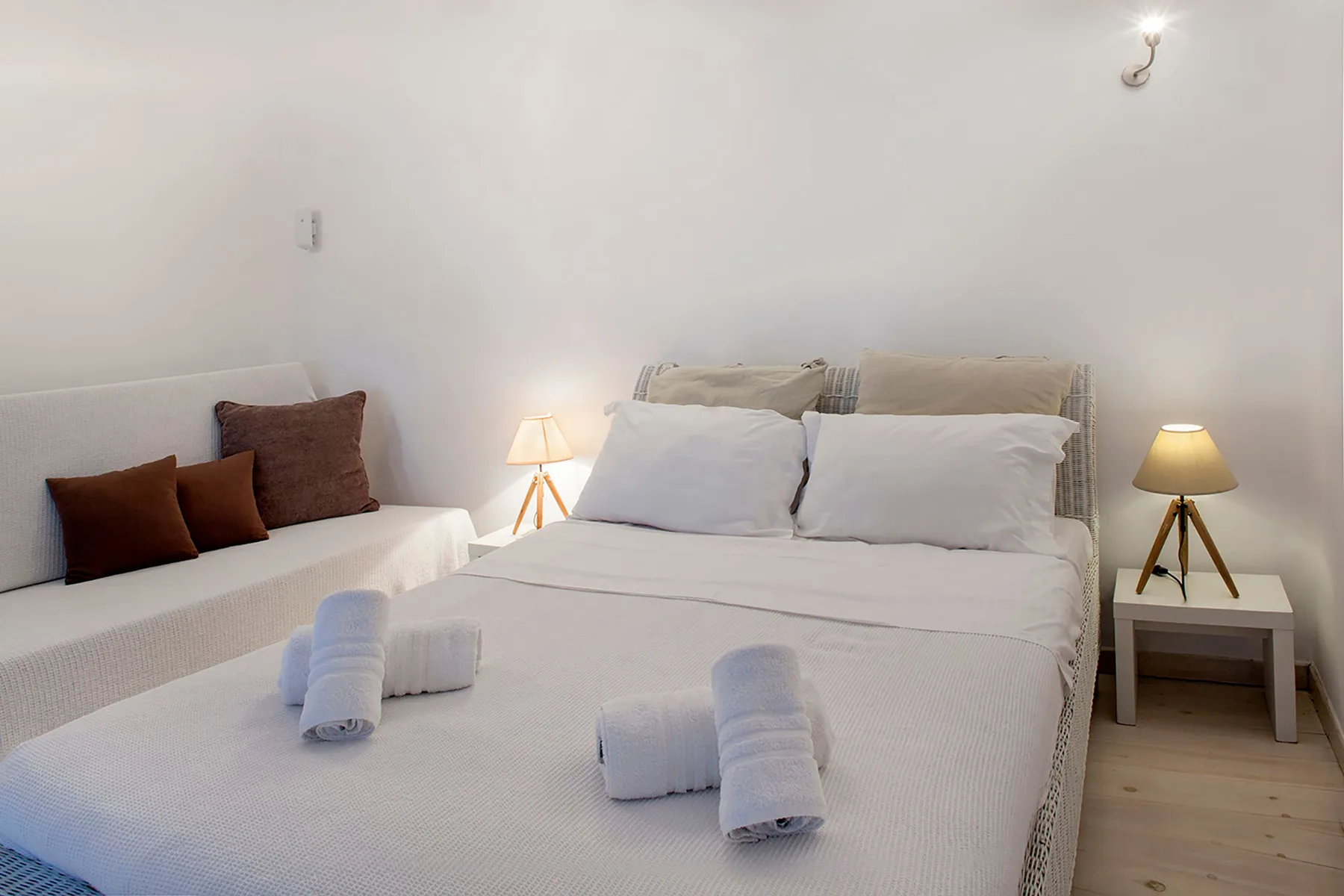 A bedroom with a large bed and a small seating area beside it.