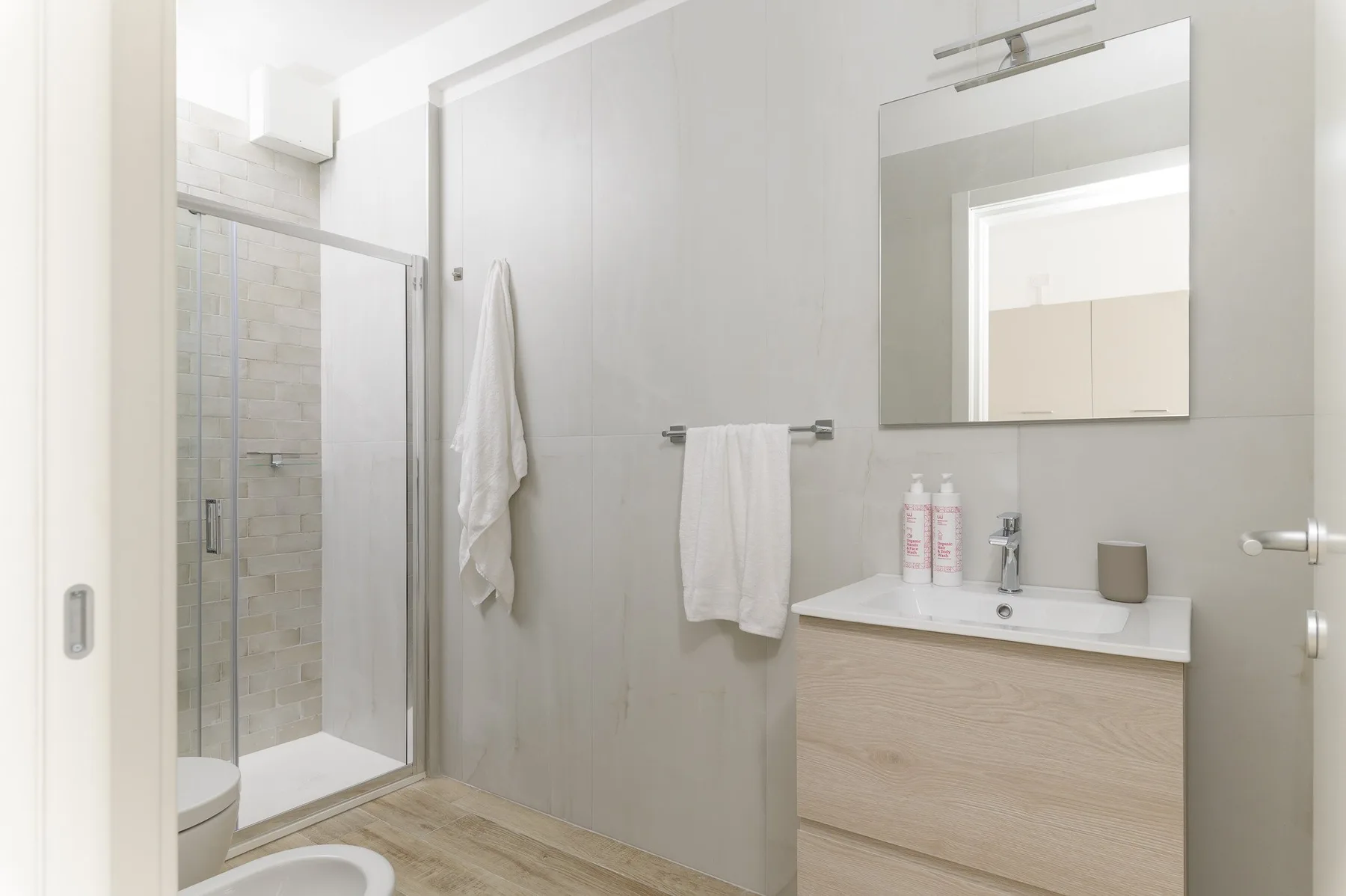 A bright bathroom with a glass shower, towels, and a vanity.