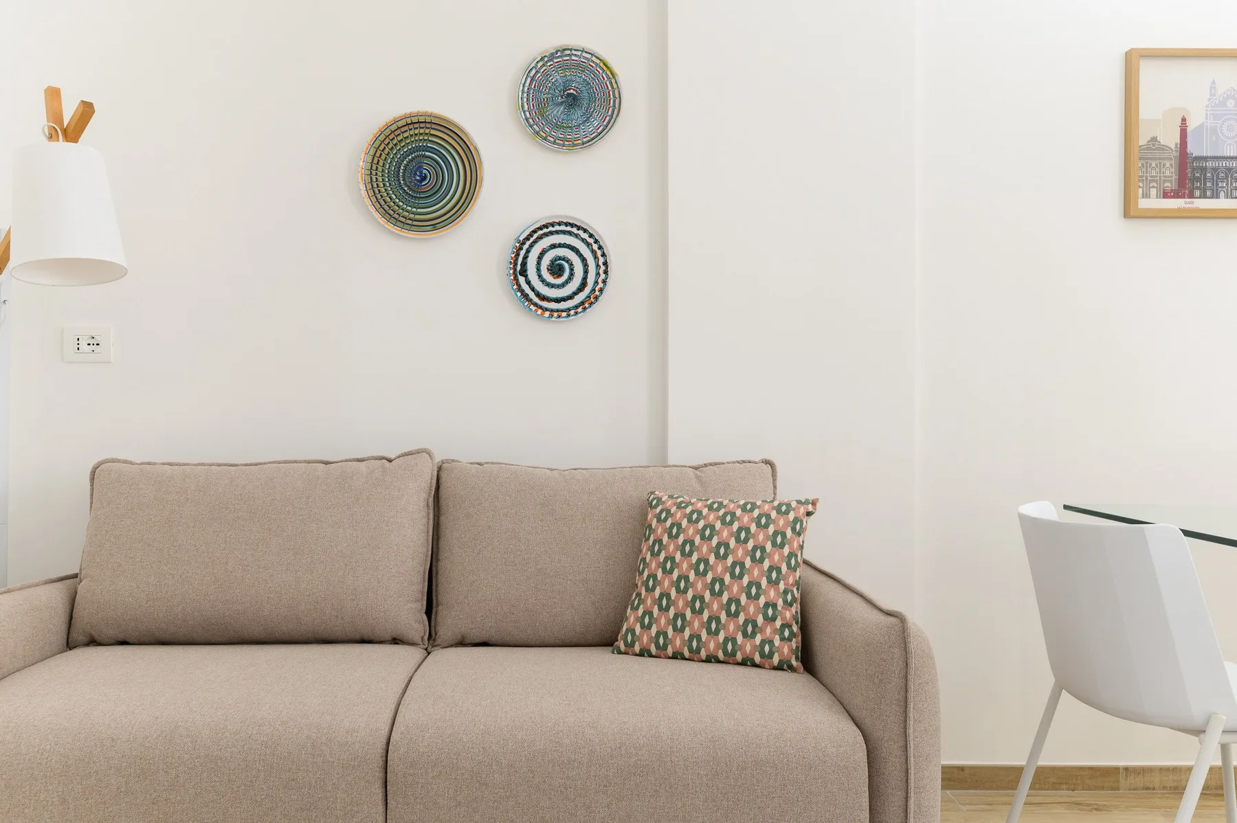 A living room with a beige sofa and decorative plates on the wall.