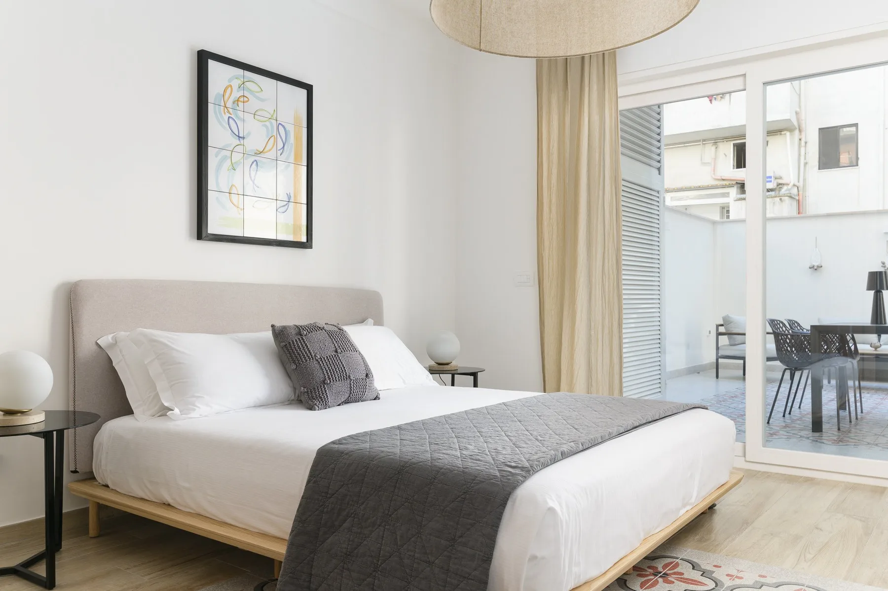 A bedroom with a neatly made bed and glass doors opening onto a patio.