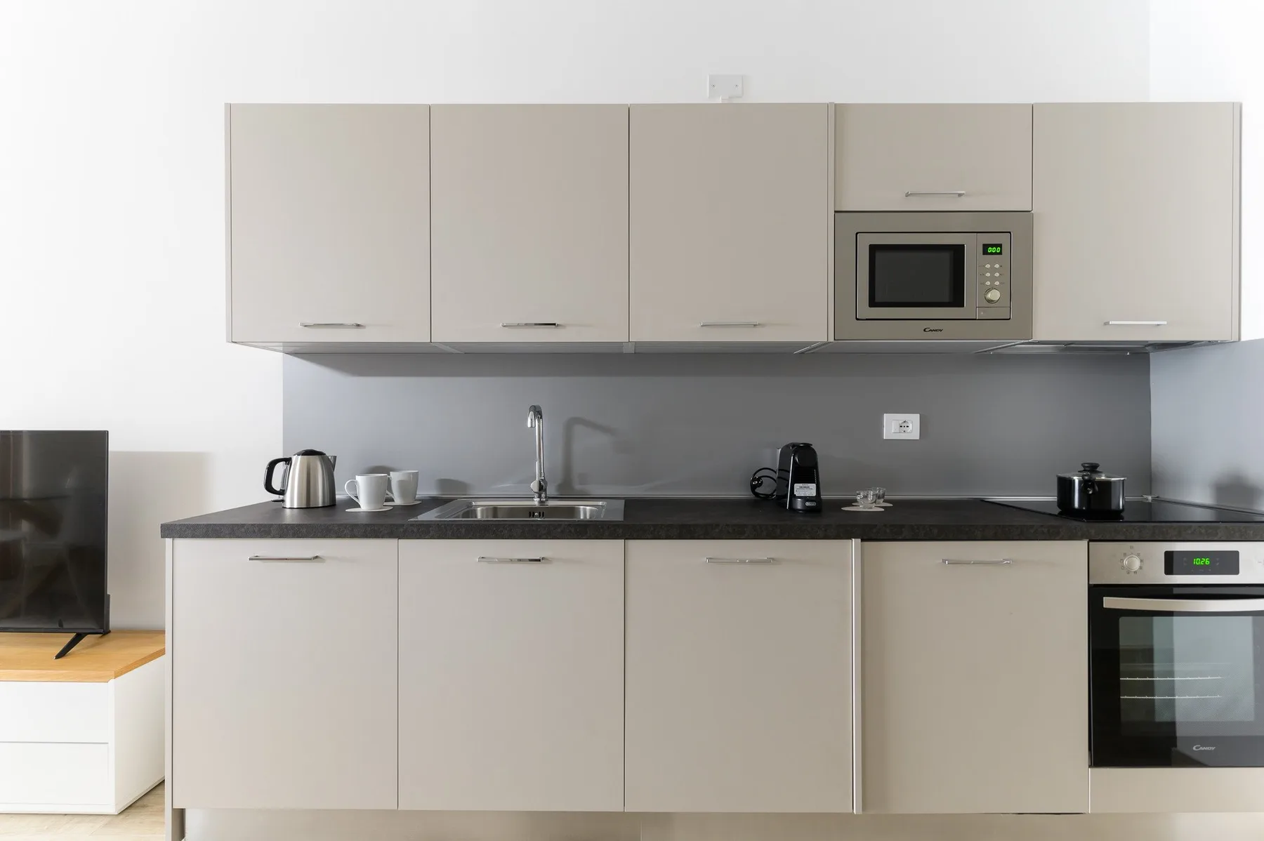 A modern kitchen with pale cabinets and a dark countertop.