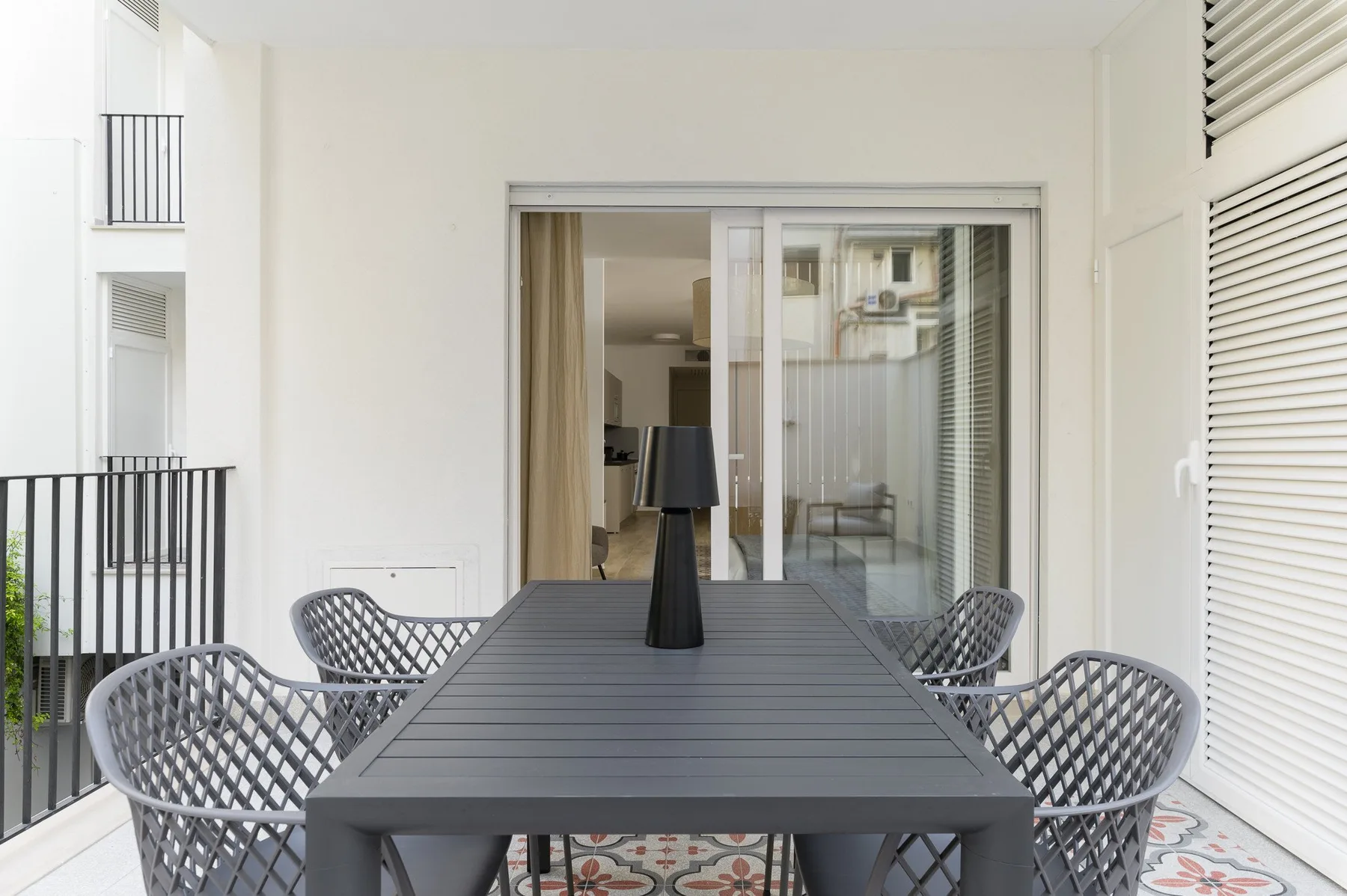 A covered patio dining area with a long table and woven seating.