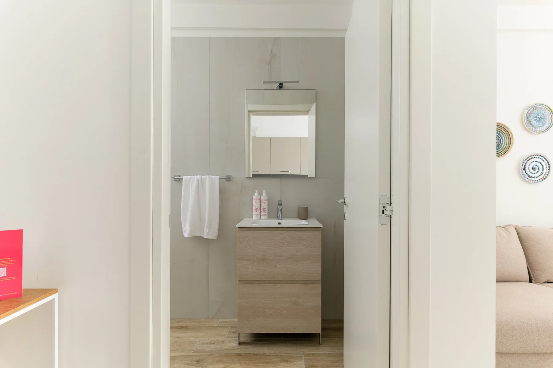 A bathroom with a sink vanity, mirror, and towel hanging on the wall.