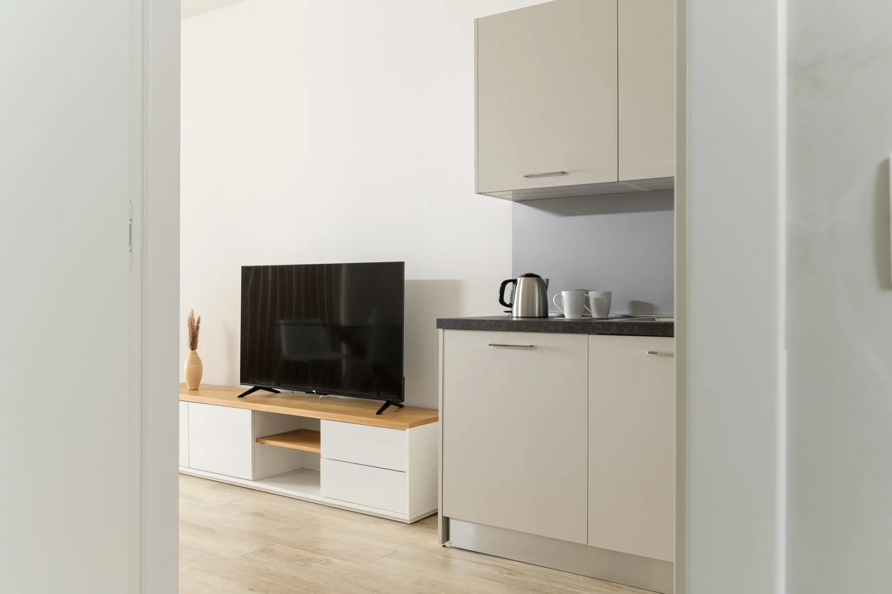 A compact kitchenette with a television on a low cabinet beside the counter.