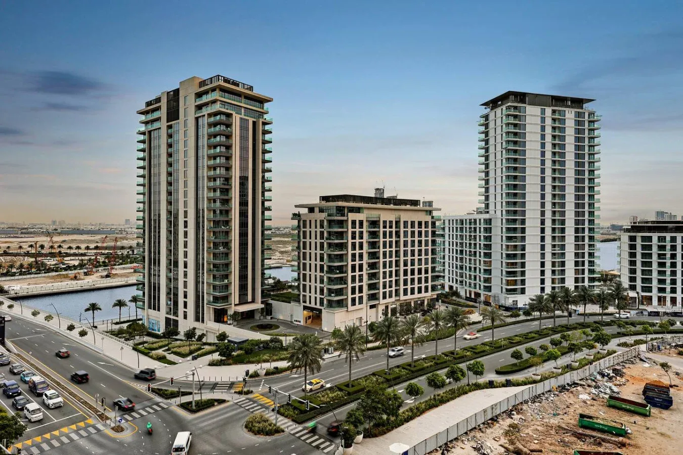 Modern high-rise buildings stand beside landscaped roads under a clear sky.