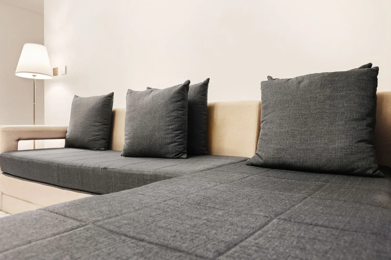 A gray seating area with dark cushions and a floor lamp.