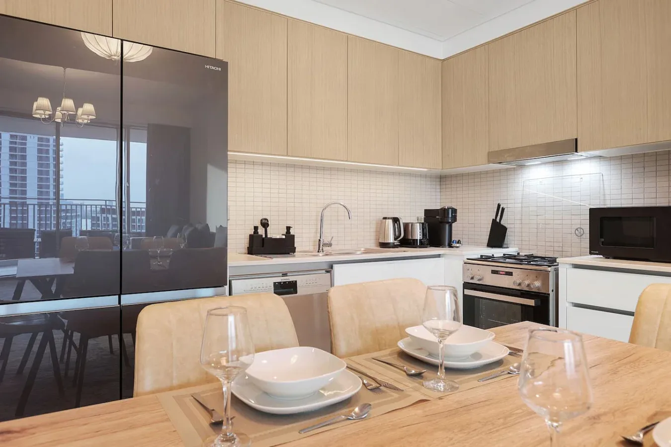 A modern kitchen and dining area with light wood cabinetry and a set table.