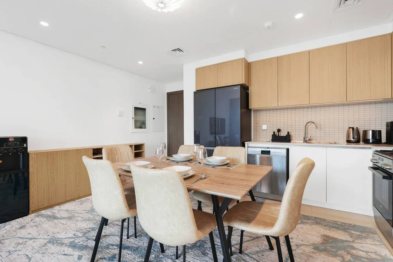 A dining area with a wooden table and chairs beside a modern kitchen.