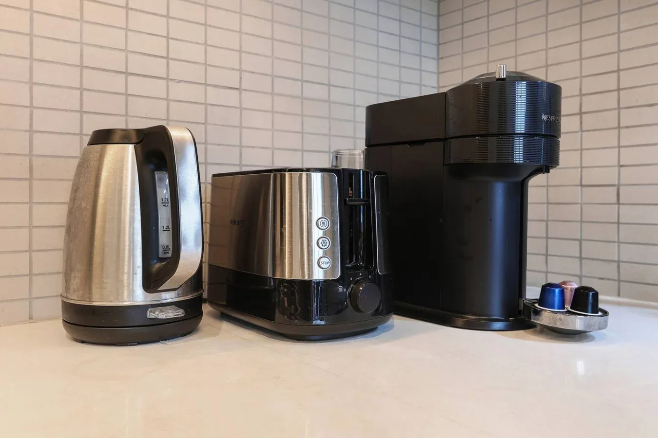 A kitchen counter with a kettle, toaster, and coffee machine.