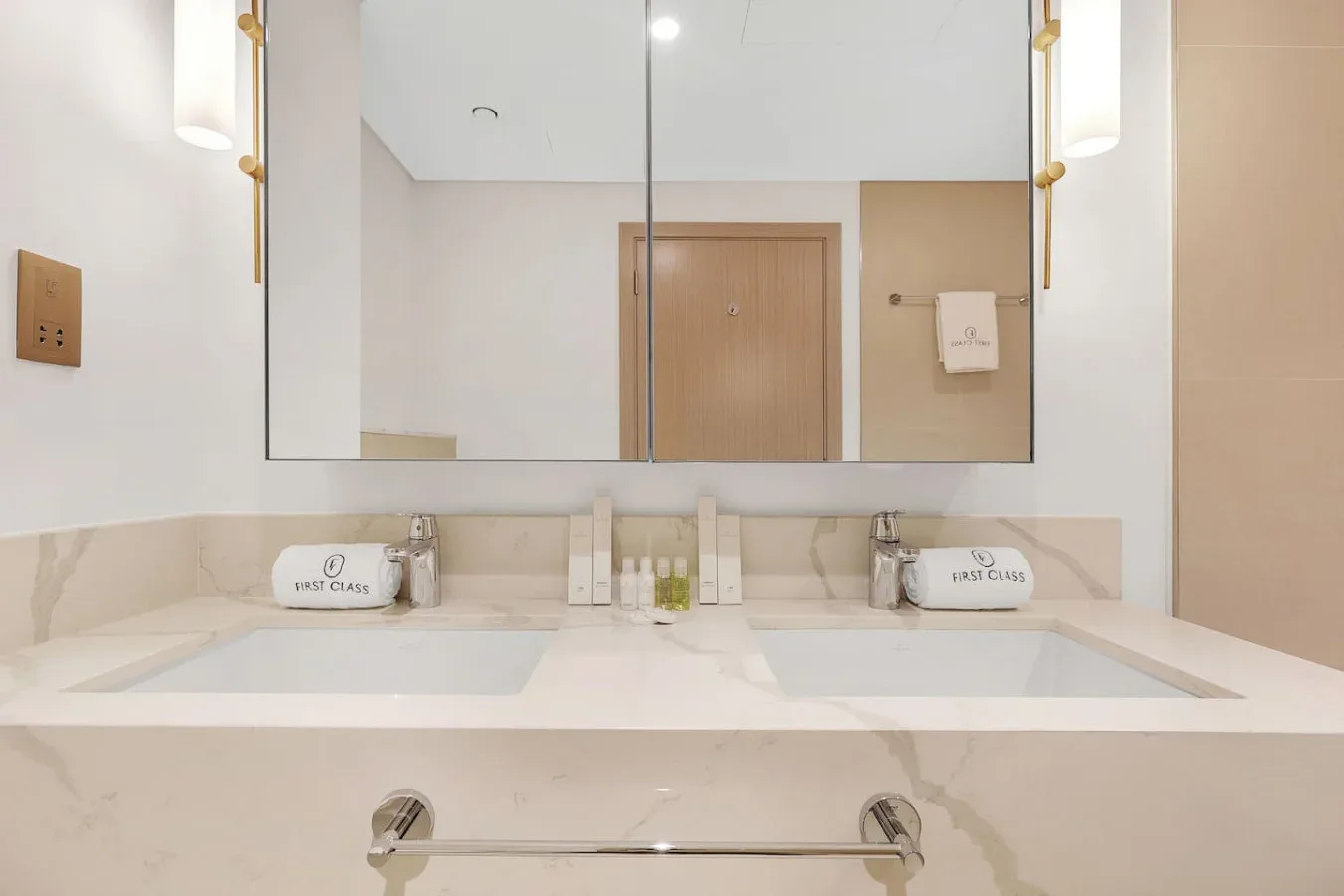 A bathroom vanity with two sinks sits beneath a wide mirror.
