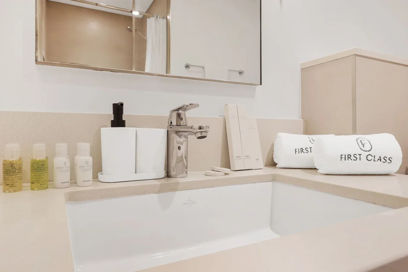 A bathroom vanity with a sink, toiletries, and folded towels.