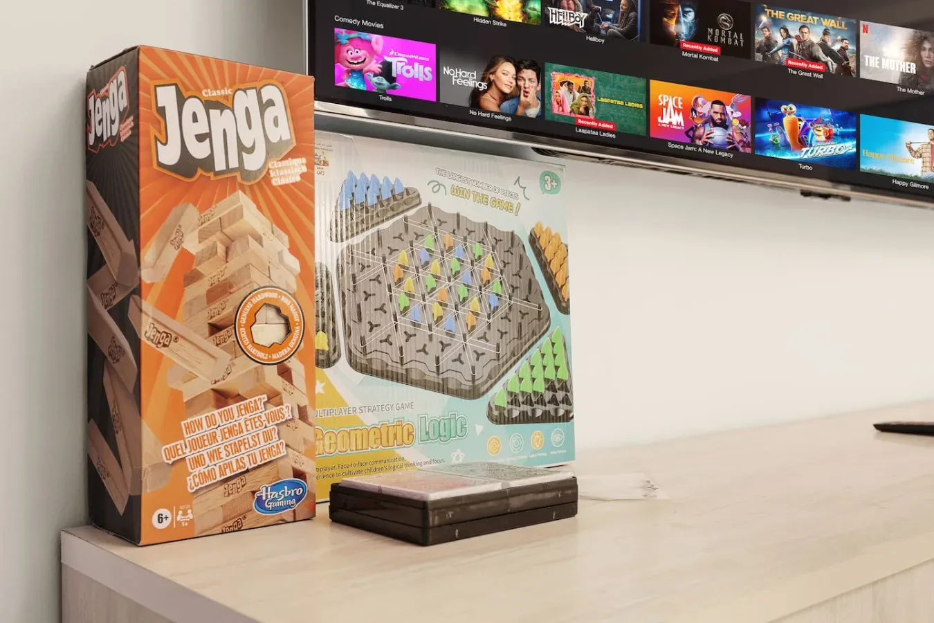 A tabletop scene with a Jenga game box and a board game beneath a television.