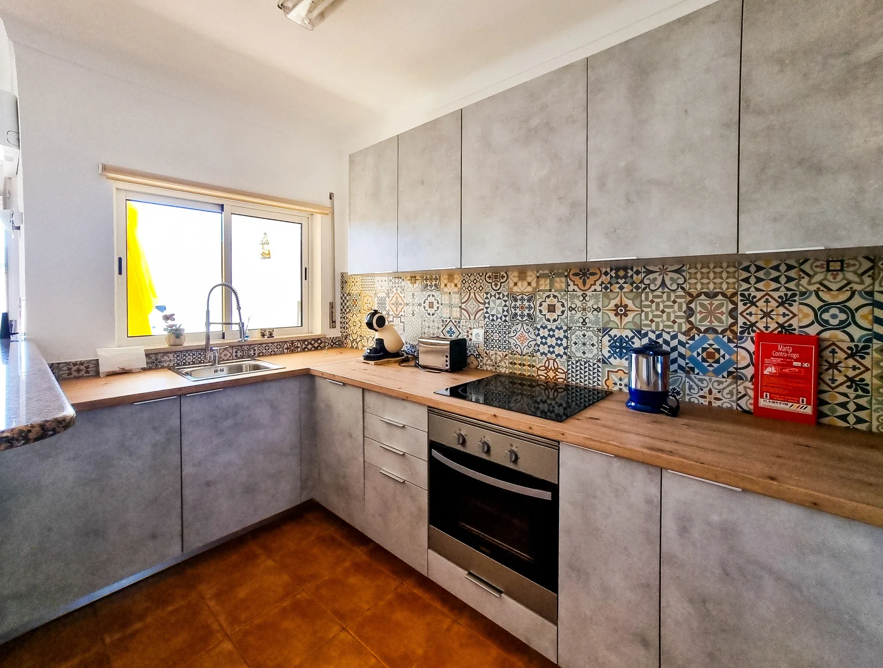 A kitchen with gray cabinets, a patterned backsplash, and a built-in oven.