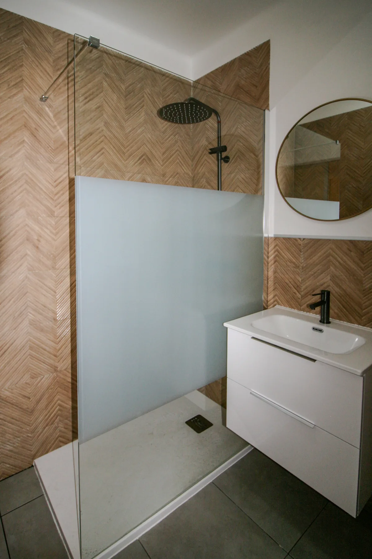A bathroom with a walk-in shower and a white vanity.