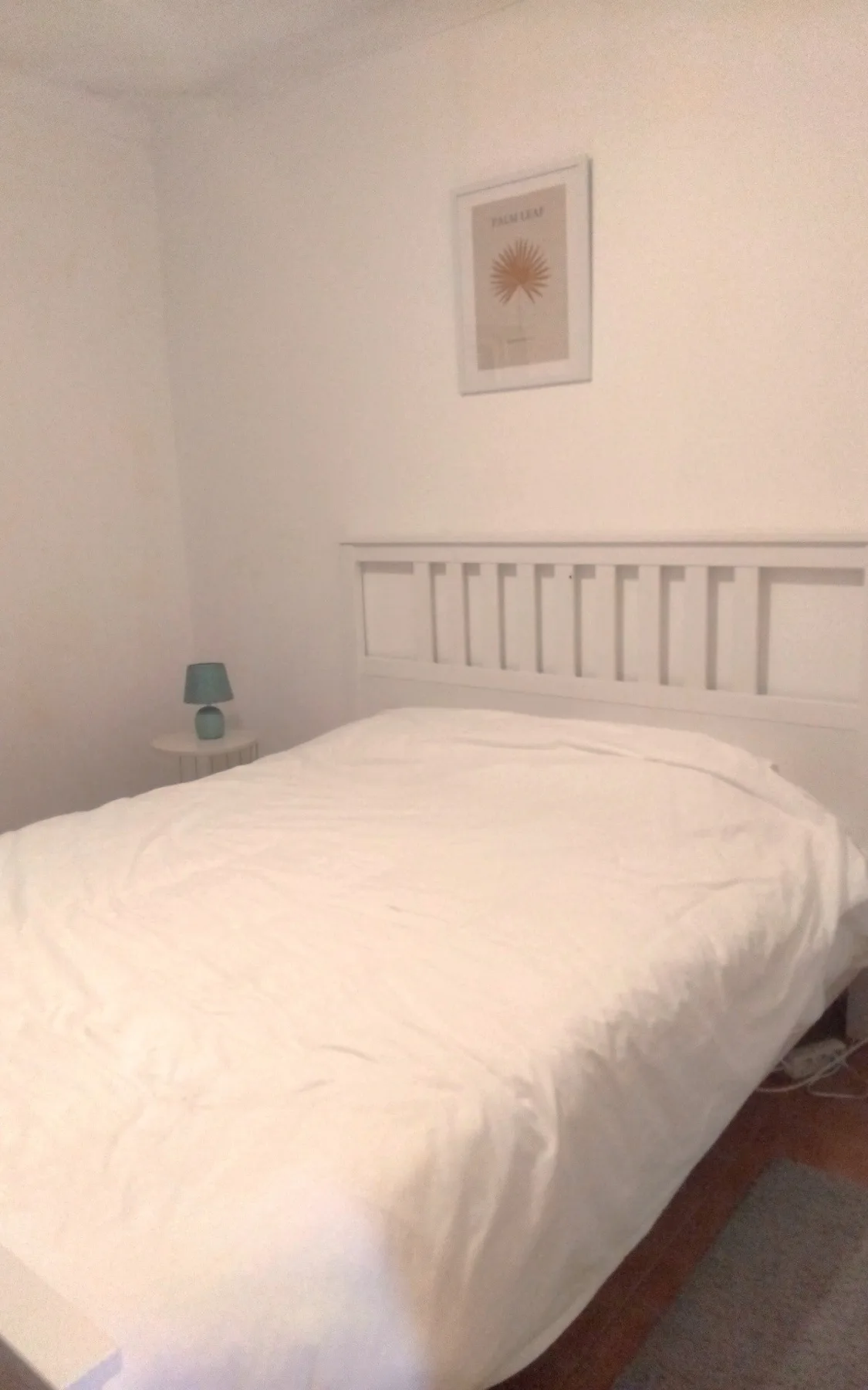 A bedroom with a neatly made bed and framed wall art.