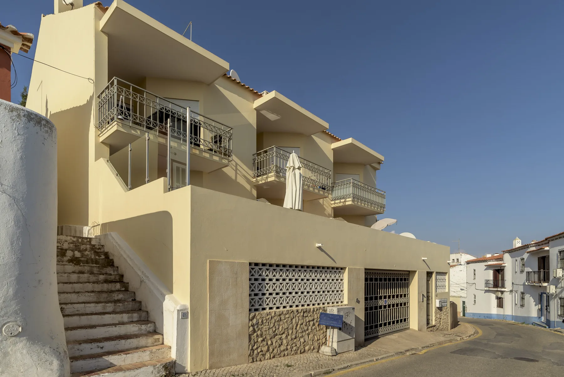 A pale apartment building faces a curving street, with balconies and exterior stairs.