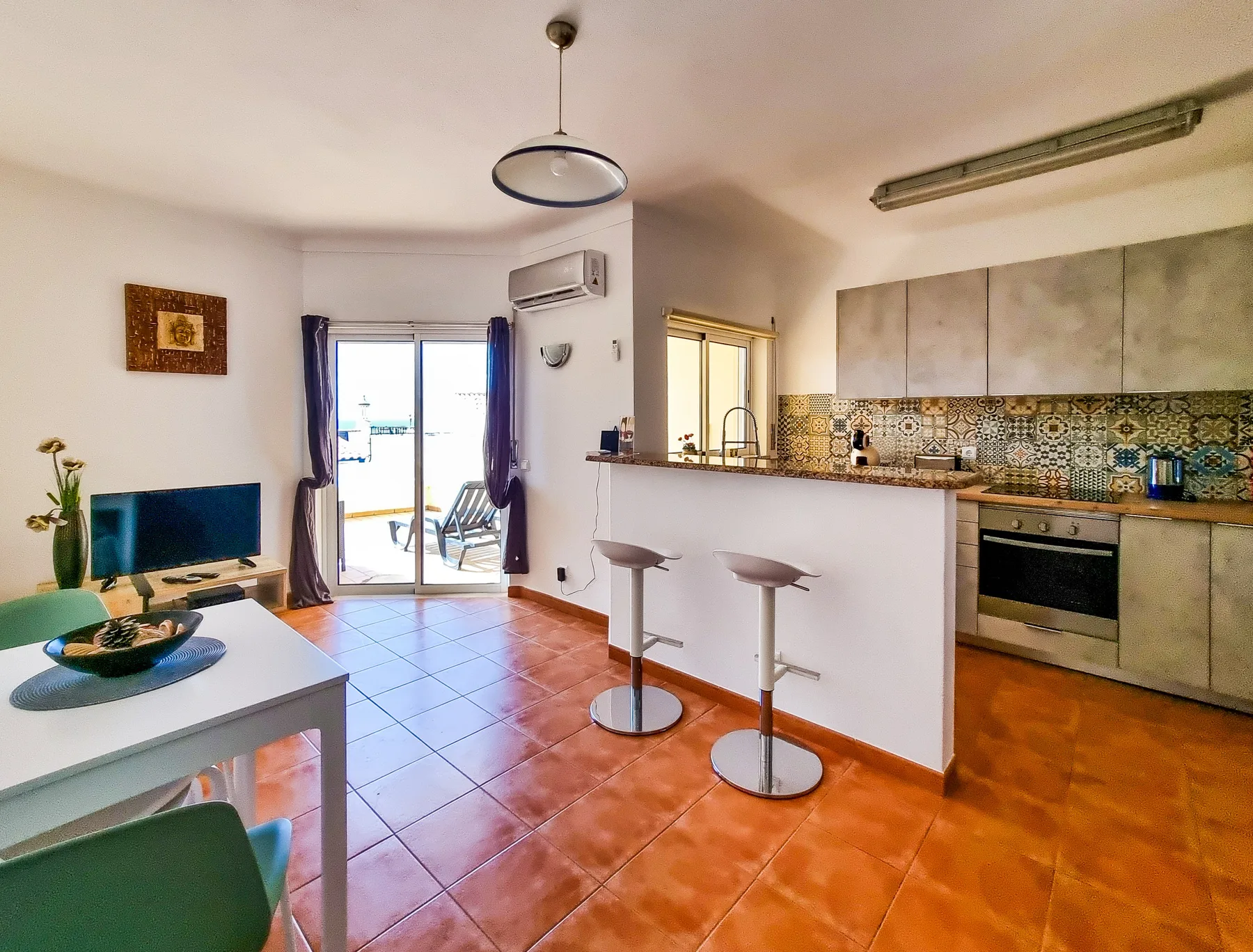 An open-plan living and kitchen area with a dining table and breakfast counter.