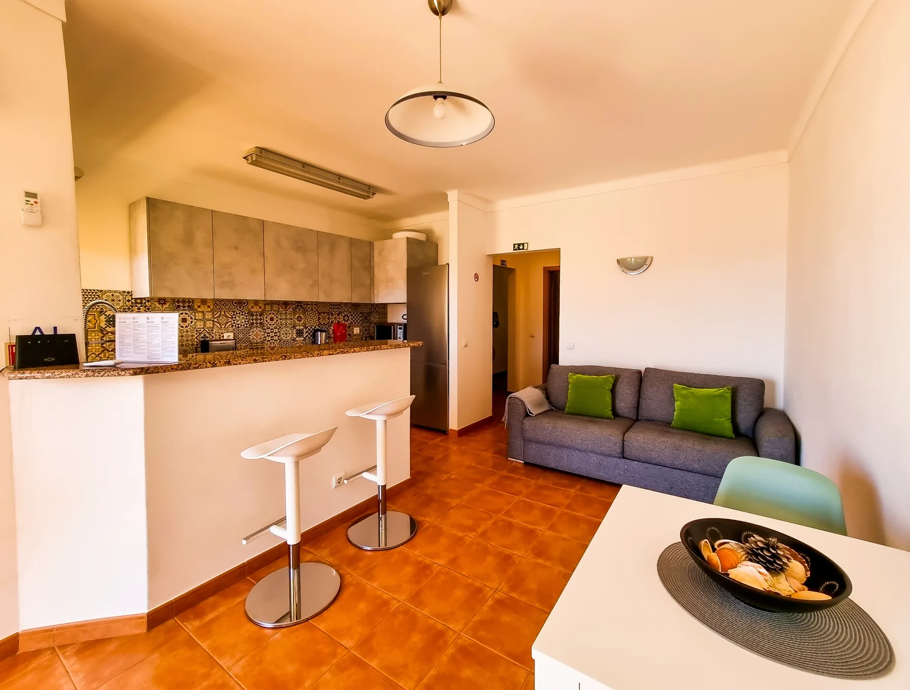 Open-plan living room with a kitchen counter and gray seating.