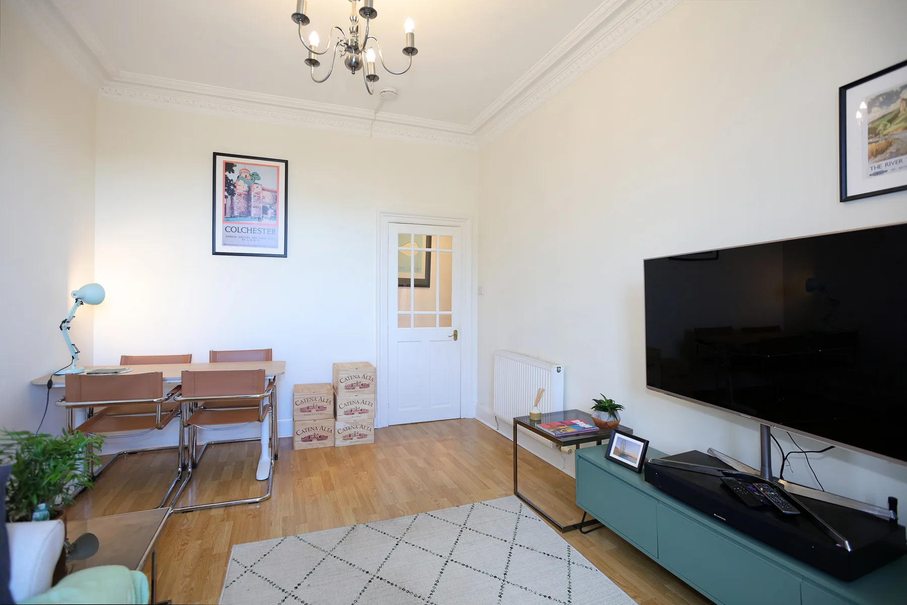 A bright living room with a dining table, television, and rug.