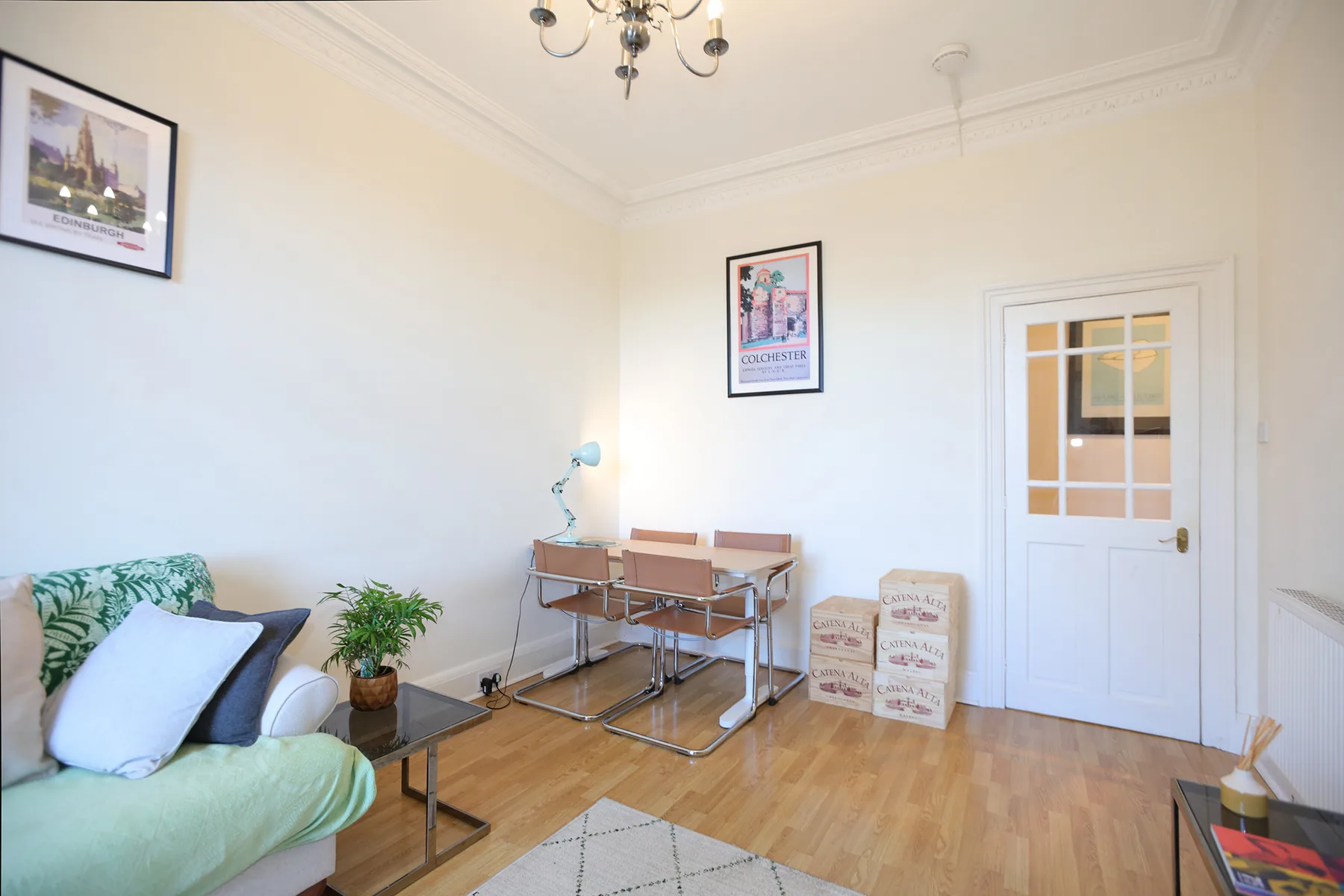 A bright living room with seating, a small table, and a white door.