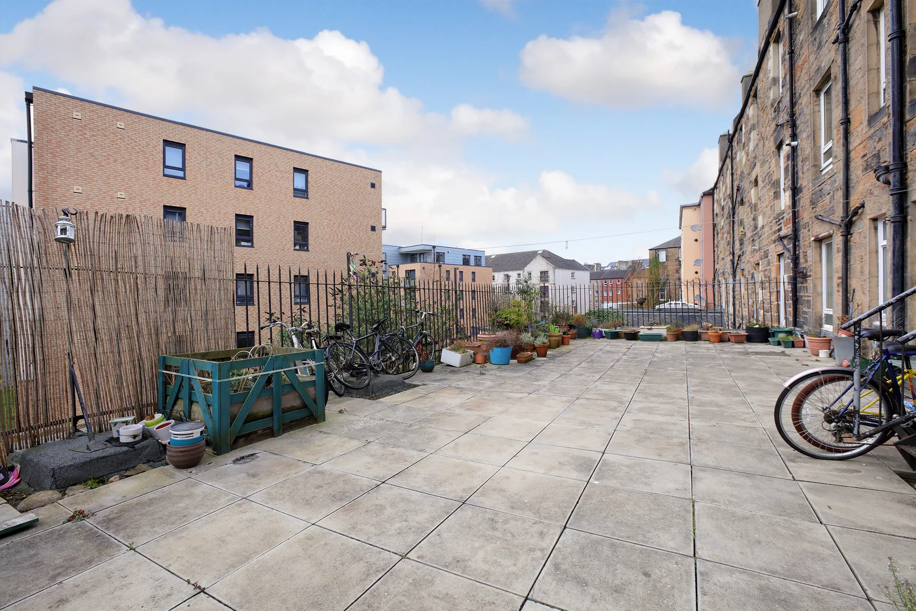 A paved courtyard with bicycles, planters, and surrounding brick buildings.