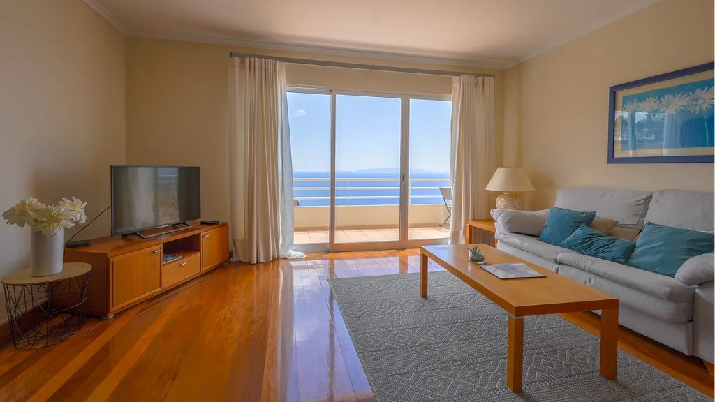 Una sala de estar con asientos, una mesa de centro y puertas corredizas de vidrio con vista al océano.