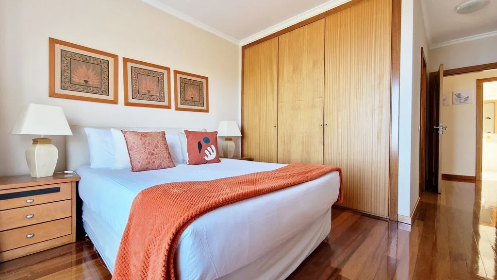 Un dormitorio con una cama, mesillas de noche y un gran armario de madera.