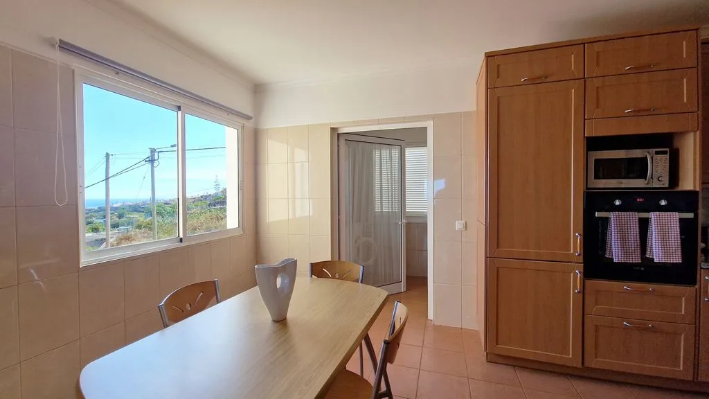 Cocina y comedor con una mesa junto a una ventana grande.
