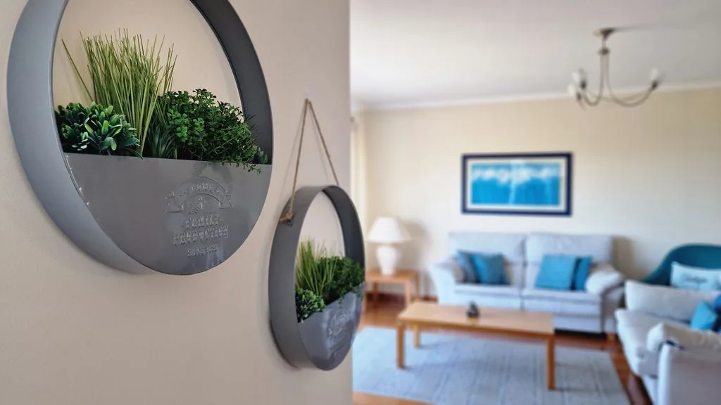 Una sala de estar con asientos azules, una mesa de centro y jardineras en la pared.