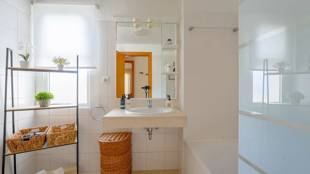 Un baño luminoso con lavabo, espejo y bañera.