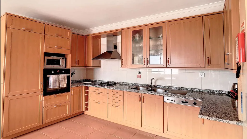 Una cocina con armarios de madera, encimera y electrodomésticos integrados.