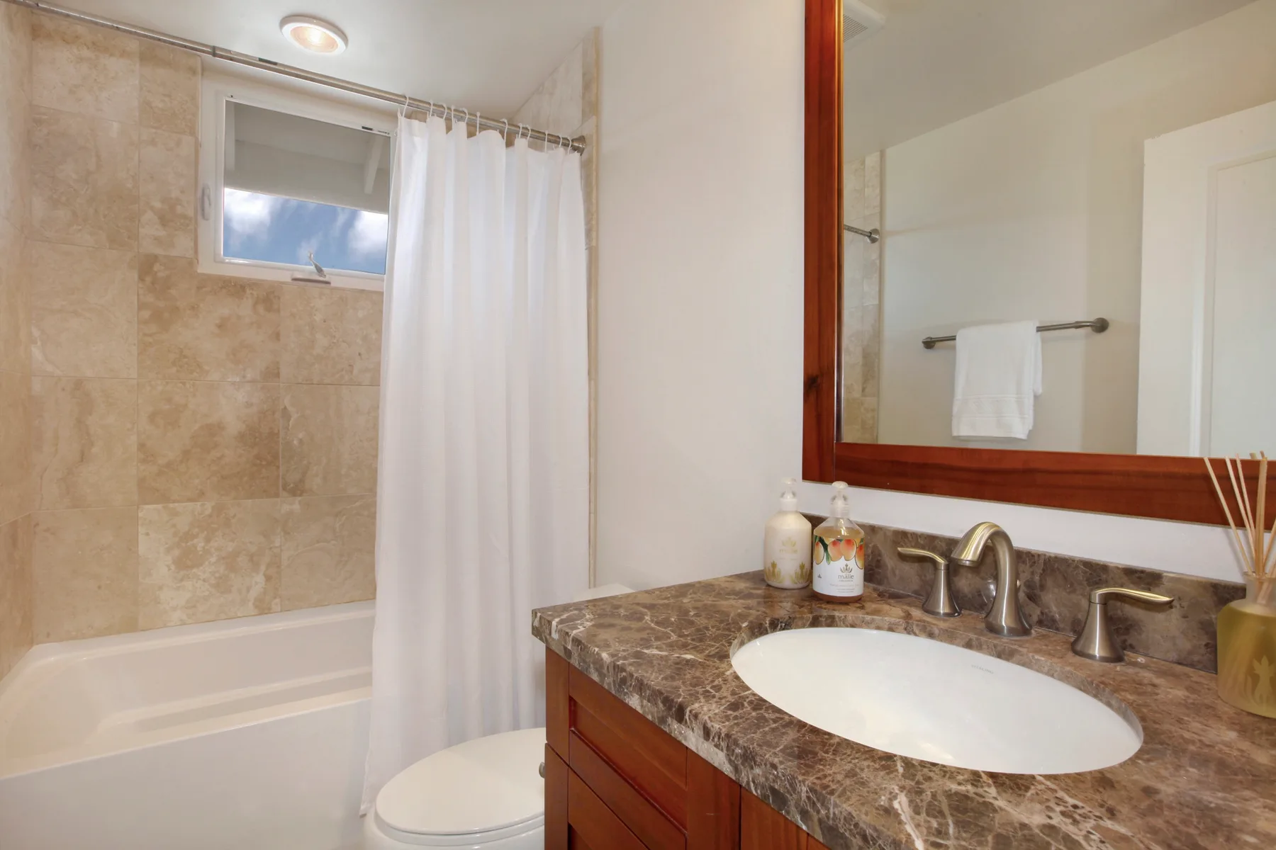 A bathroom with a bathtub, shower curtain, and sink vanity.