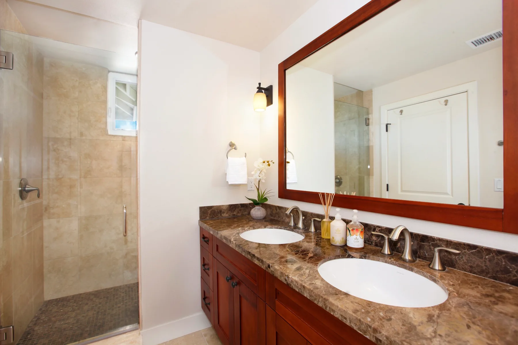 A bathroom vanity with two sinks sits beside a glass shower.