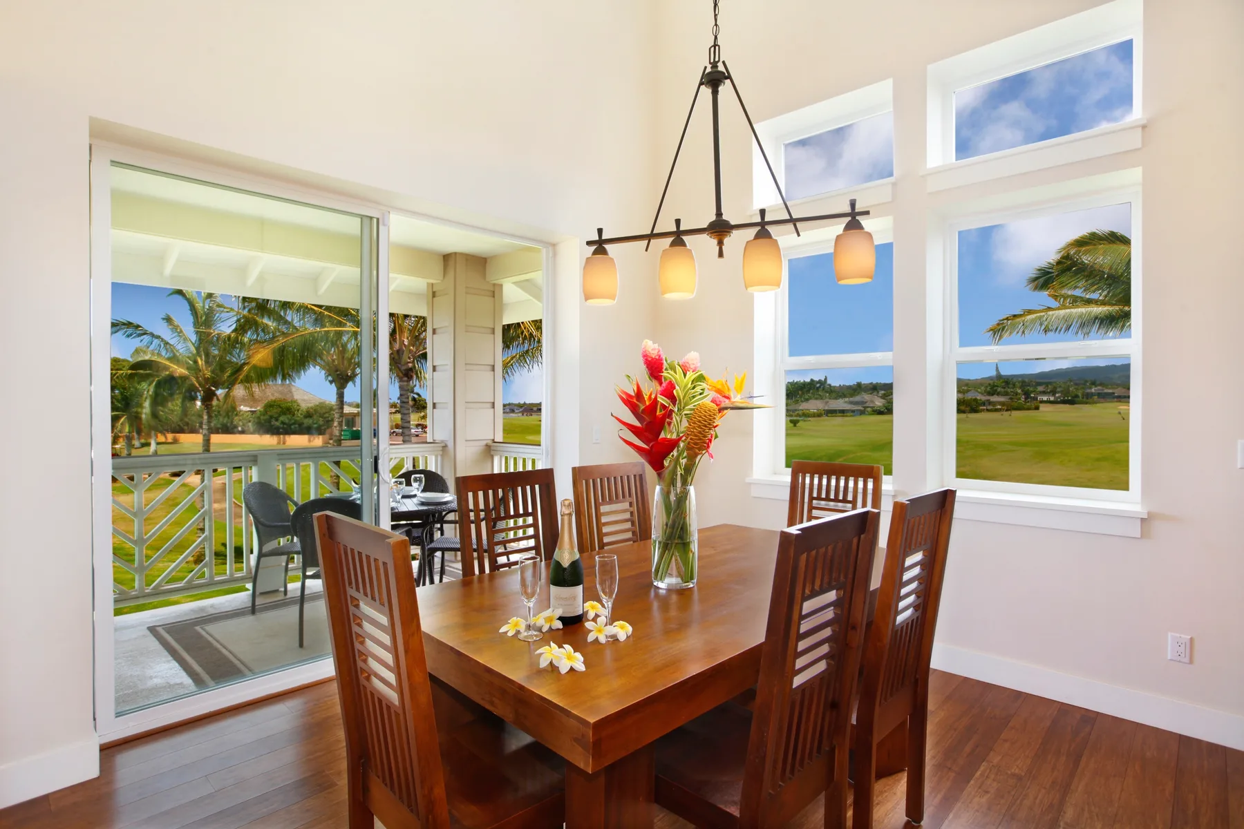 A dining area with a wooden table and large windows overlooking greenery.