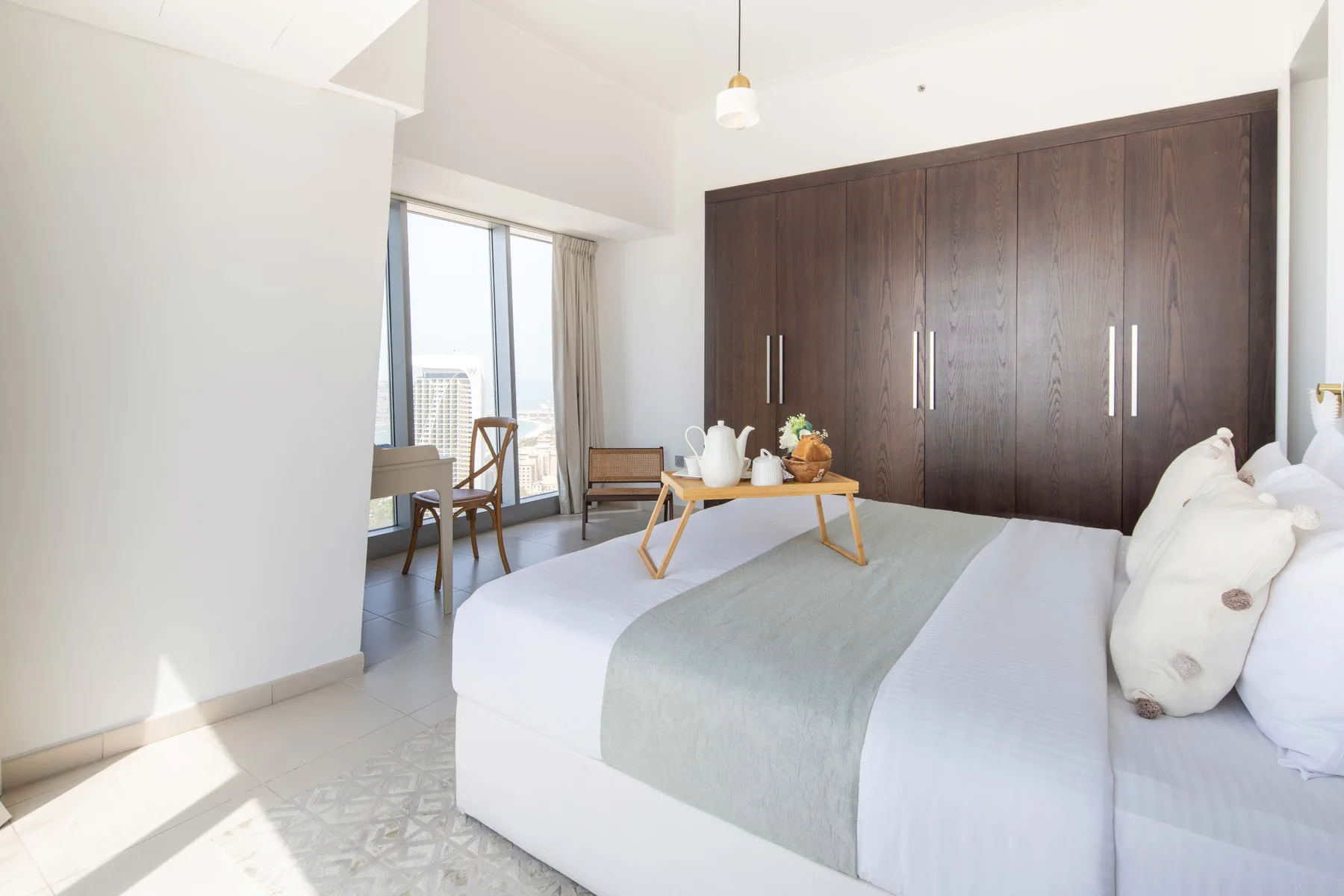 Un dormitorio luminoso con una cama grande y armarios de madera oscura.