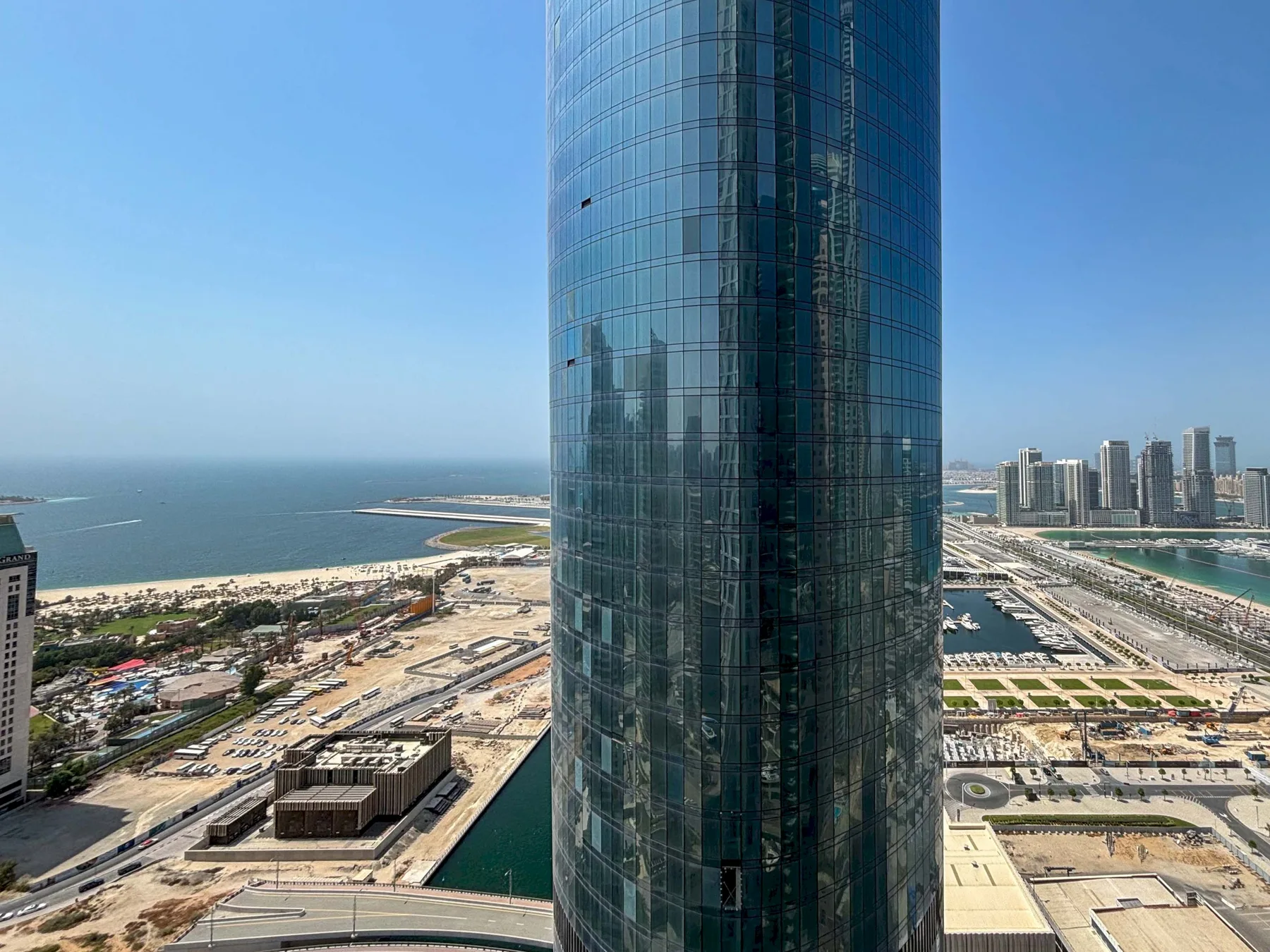 Una torre de vidrio domina una zona costera con edificios cercanos.