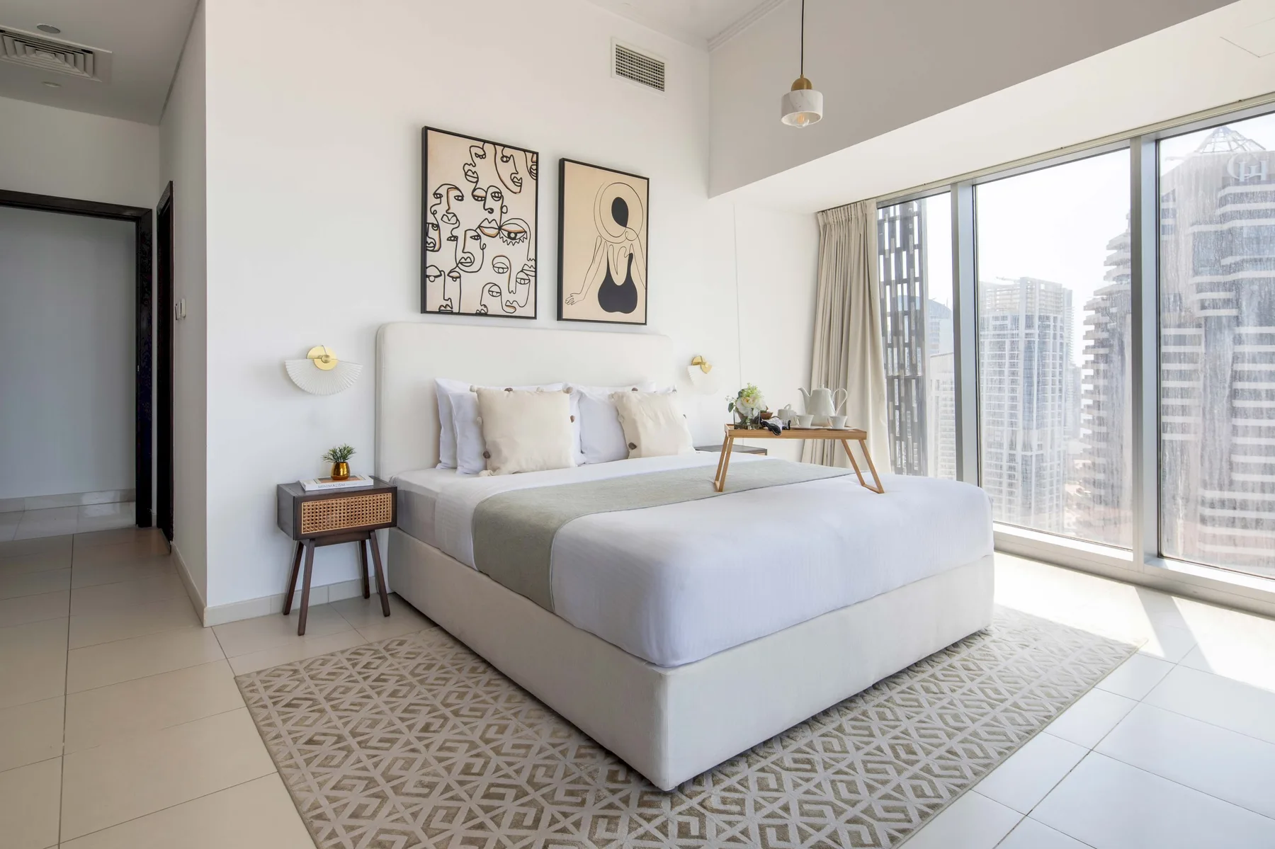 Un dormitorio luminoso con una cama bien tendida y grandes ventanales.