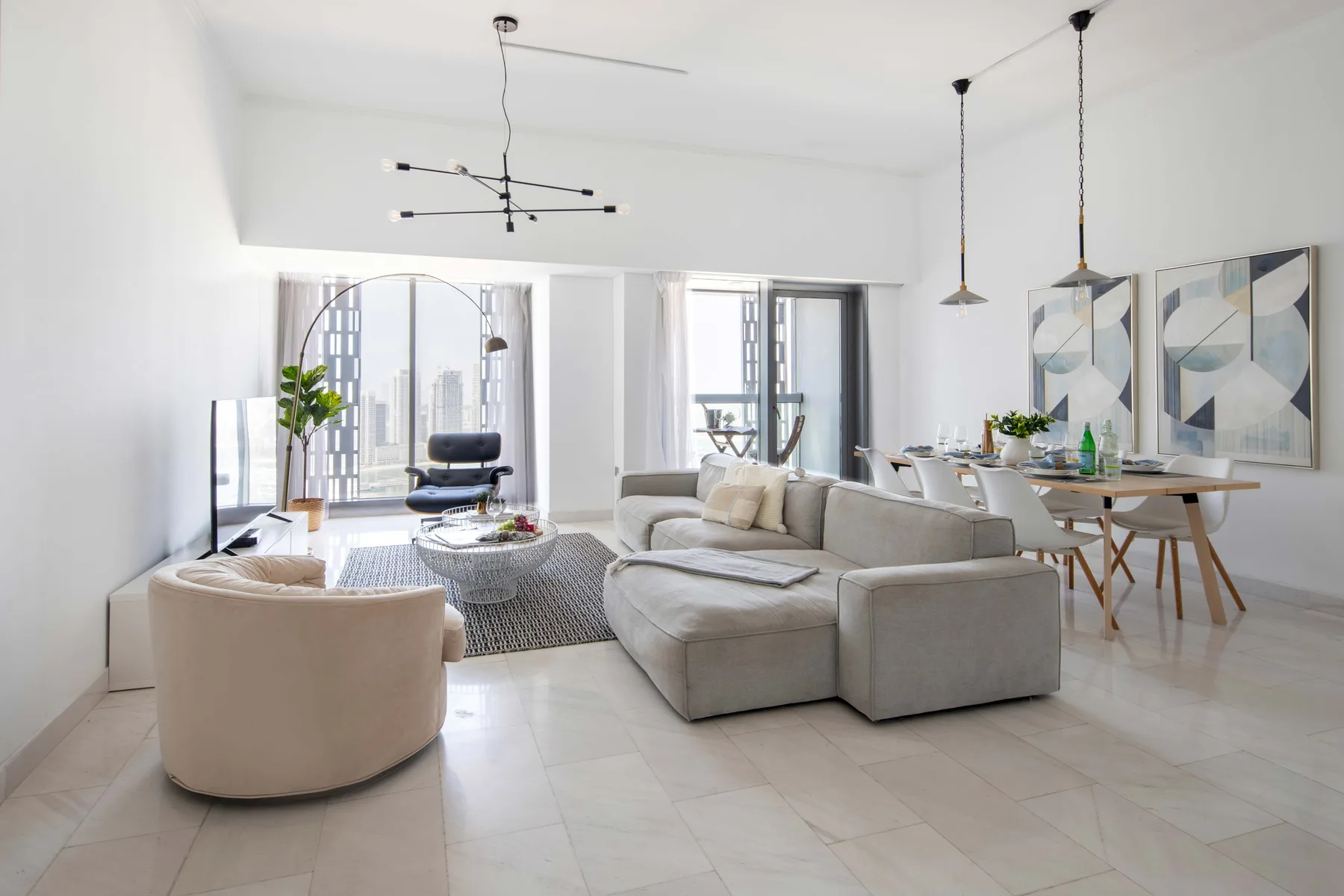Una sala luminosa con asientos y una mesa de comedor junto a grandes ventanas.