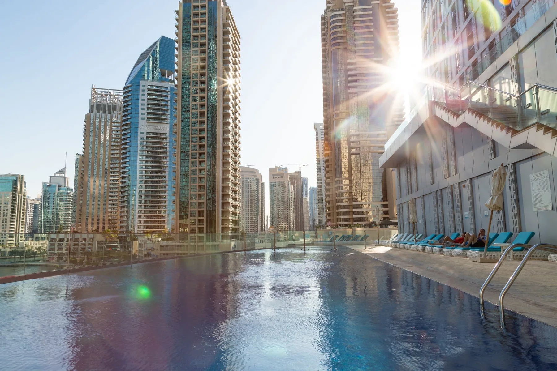 Una piscina en la azotea ofrece vistas de altos edificios de la ciudad bajo el sol.