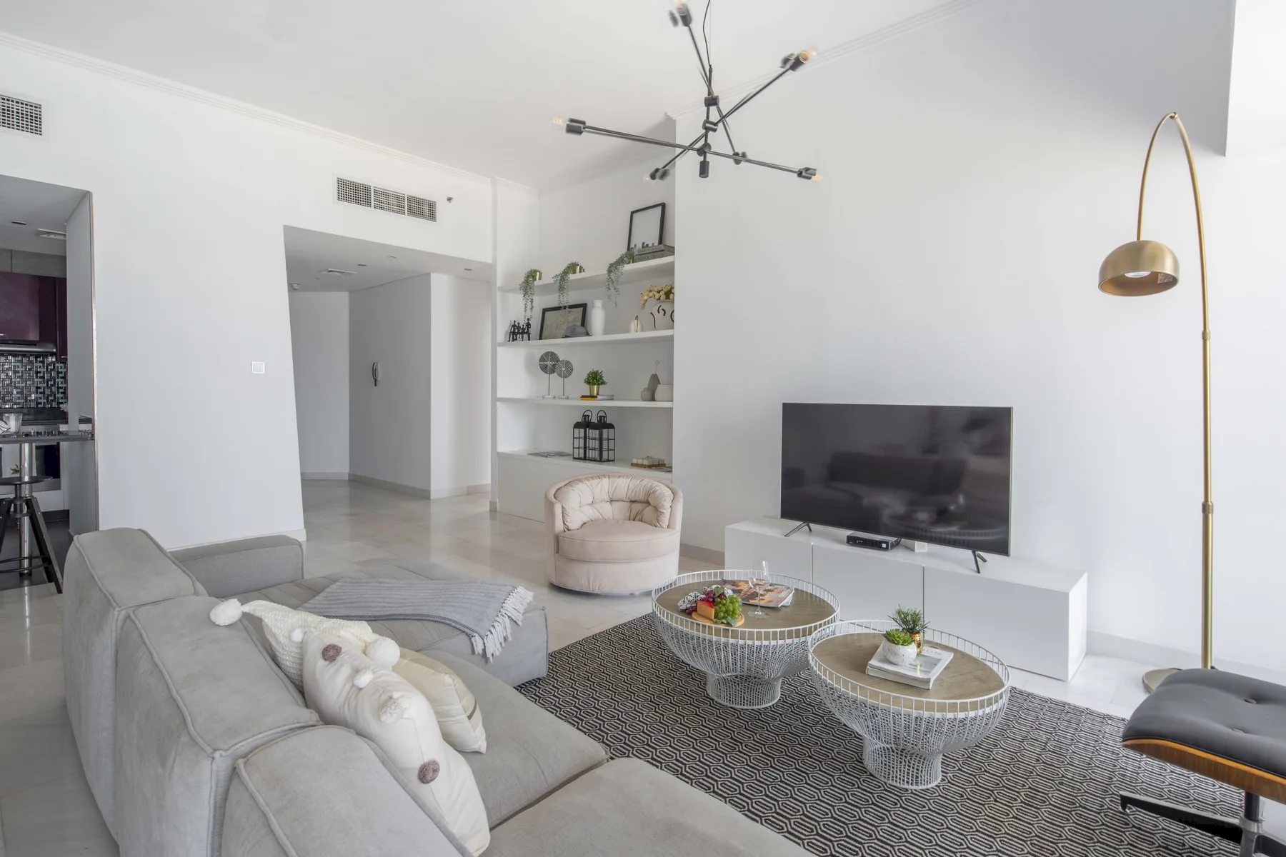 Una sala luminosa con asientos, un televisor y dos mesas de centro.
