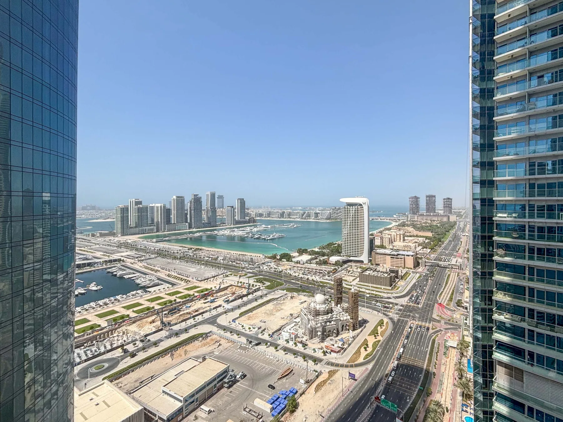 El horizonte de una ciudad costera y una marina se ven más allá de varias vías.