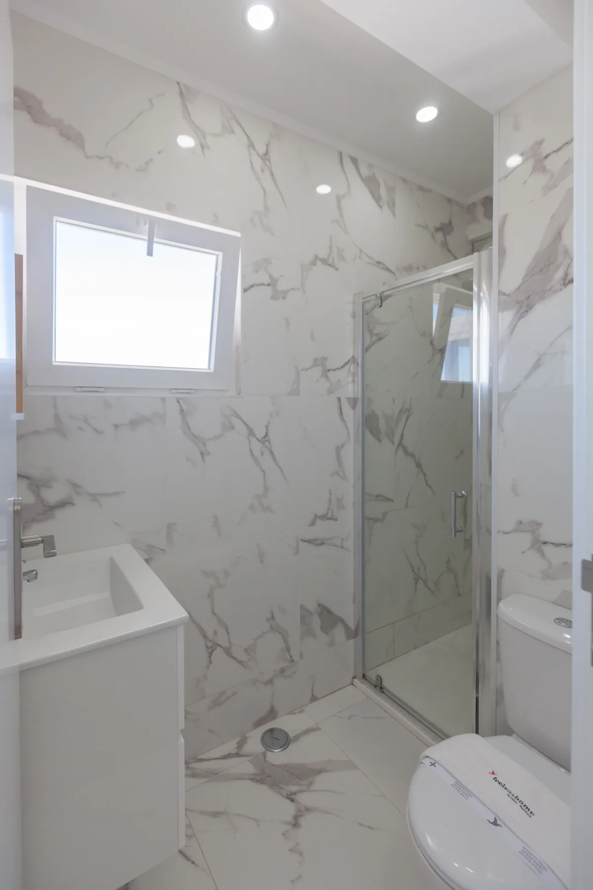 A bathroom with a glass shower, sink, and toilet.