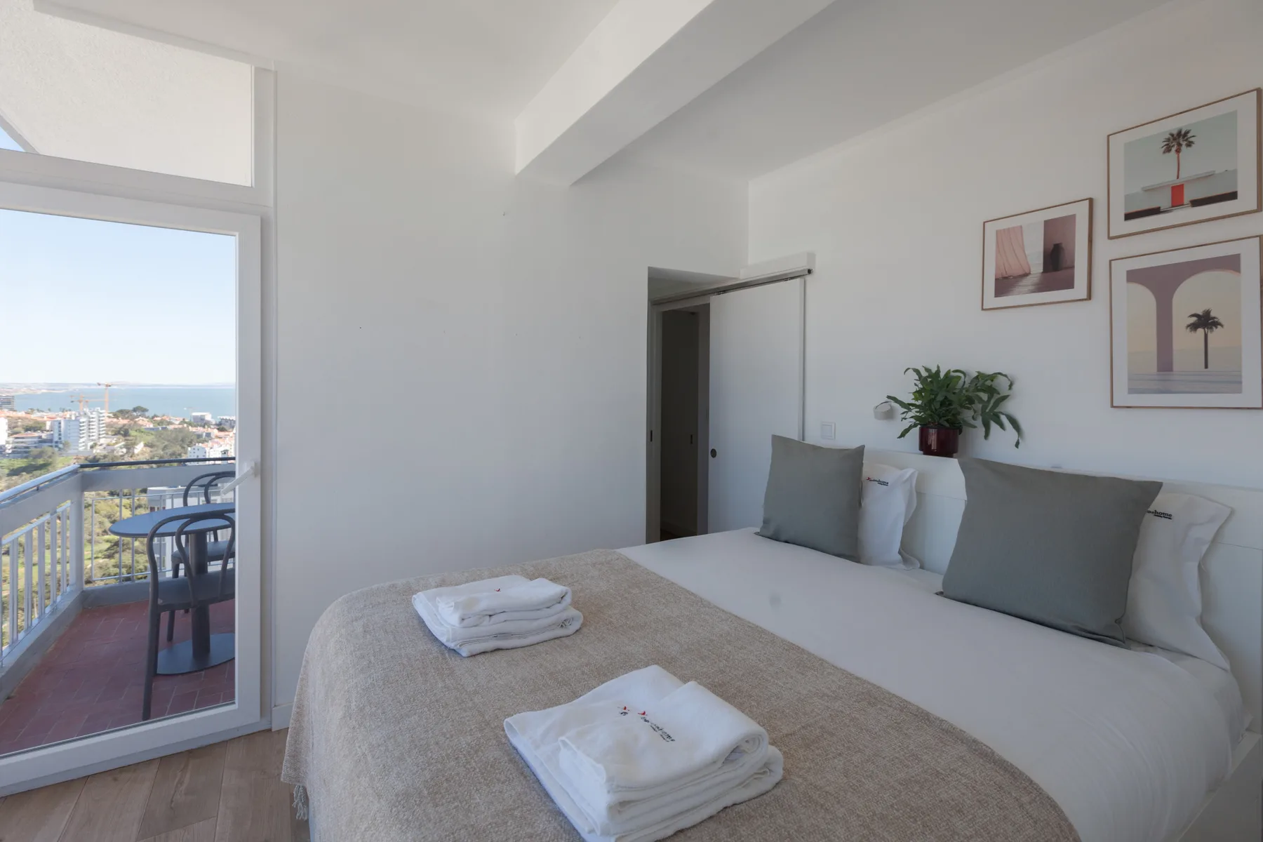A bright bedroom opens onto a balcony with a view of the sea.