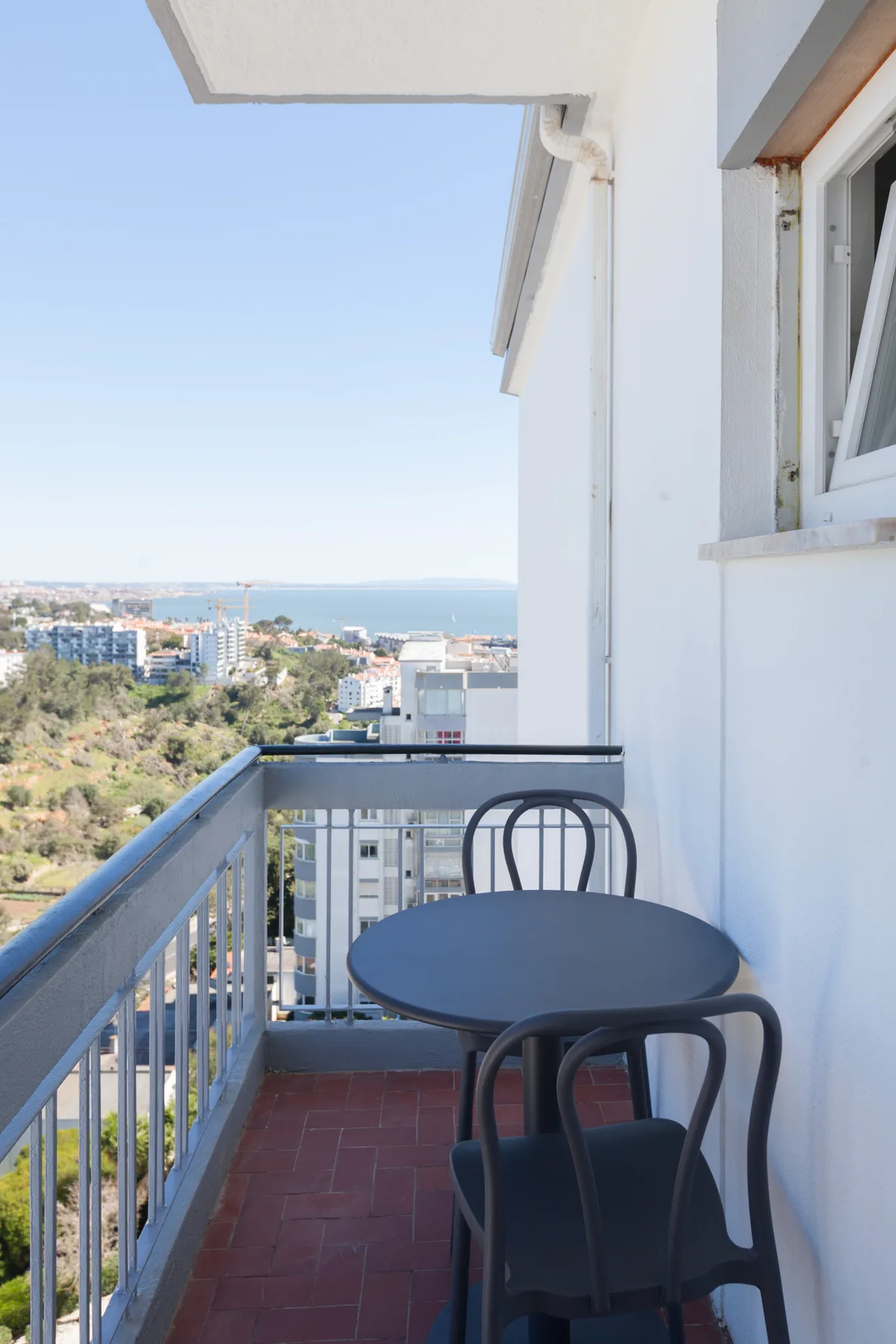 A small balcony with a round table overlooks the coast.